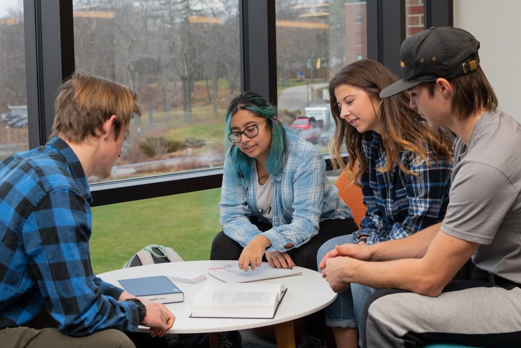 Four U N E students sit studying around a table in the Ripich Commons